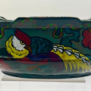 May include: A dark blue ceramic bowl with a colourful design of a bird and flowers. The bowl has a scalloped rim and a glossy finish.