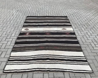 May include: A black and white striped rug with brown accents. The rug has a traditional design with geometric patterns.