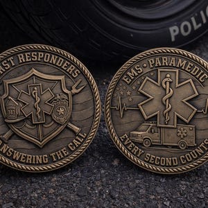 May include: Two bronze coins with detailed designs. One coin reads "FIRST RESPONDERS ANSWERING THE CALL" with a shield, axe, and badge. The other coin says "EMS PARAMEDIC EVERY SECOND COUNTS" with an ambulance and medical symbol.