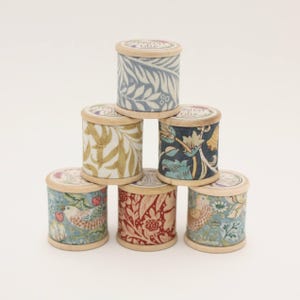 Może przedstawiać: Sześć drewnianych szpulek nici z różnymi wzorami kwiatowymi i ptaków. Szpulki są ułożone w kształcie piramidy.