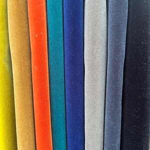 May include: A close-up of eight fabric swatches in different colors, including yellow, orange, teal, blue, gray, and black. The fabric has a soft, velvety texture.