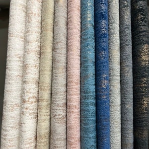 May include: Close-up of fabric swatches in various colors and textures. The fabrics have a subtle shimmer and a textured, woven appearance. The colors include white, beige, gray, pink, blue, and black.