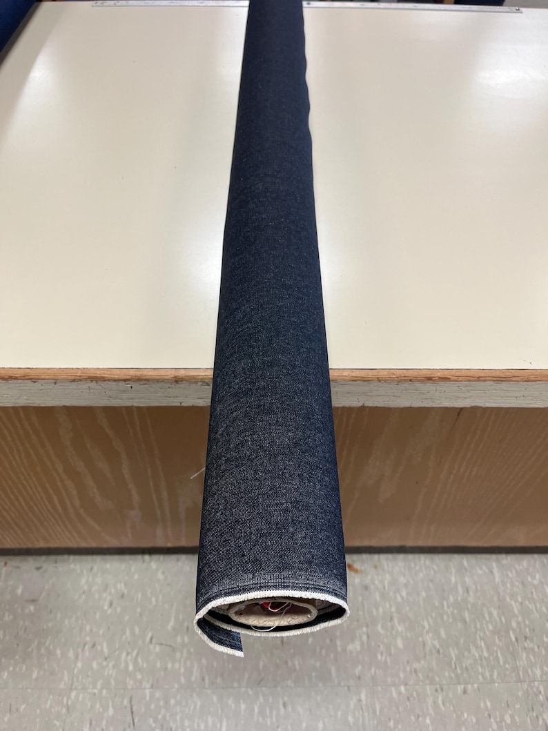 May include: A roll of dark blue denim fabric with white stitching.