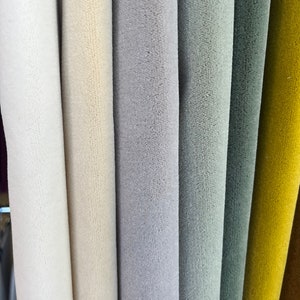May include: Close-up of fabric swatches in various colors, including white, cream, gray, light blue, dark blue, yellow, and brown. The fabric has a soft, fuzzy texture.