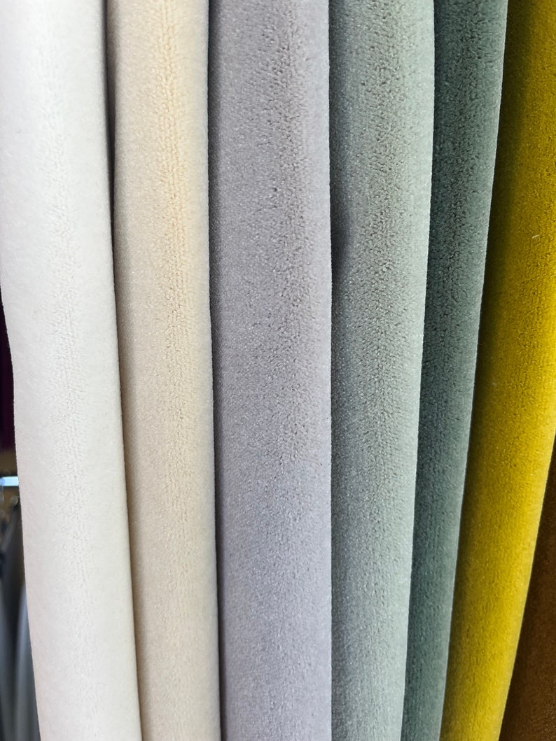 May include: Close-up of fabric swatches in various colors, including white, cream, gray, light blue, dark blue, yellow, and brown. The fabric has a soft, fuzzy texture.