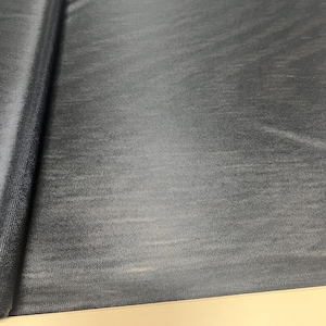 May include: Black fabric with a subtle textured pattern. The fabric is rolled up on the left side of the image.