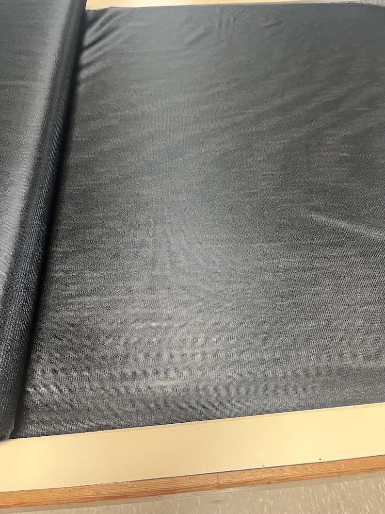 May include: Black fabric with a subtle textured pattern. The fabric is rolled up on the left side of the image.