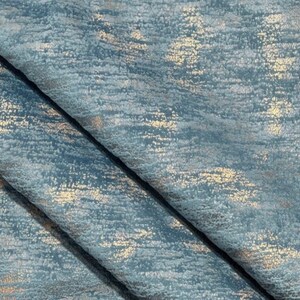 May include: Close-up of a blue fabric with a subtle metallic sheen. The fabric has a textured, woven appearance with a subtle shimmer.