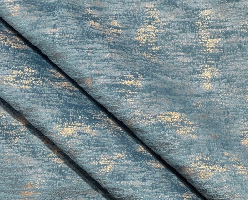 May include: Close-up of a blue fabric with a subtle metallic sheen. The fabric has a textured, woven appearance with a subtle shimmer.