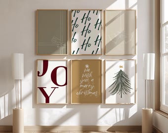 May include: A collection of six framed art prints with a Christmas theme. The prints feature minimalist designs, including the word "JOY", "Ho Ho Ho" text, a Christmas tree, and the phrase "We wish you a merry Christmas". The frames have a gold finish.