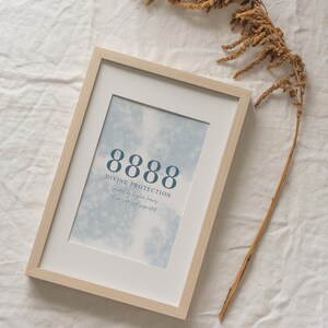 Peut inclure: Une impression encadrée avec un fond aquarelle bleu et le nombre 8888 en bleu foncé. Le texte "Divine Protection" est sous le nombre, suivi du texte "Guidé par des forces supérieures, vous êtes en sécurité et soutenu."