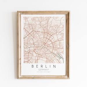 May include: A framed map print of Berlin, Germany, with a beige background and brown lines representing streets. The text "BERLIN GERMANY" is printed below the map.