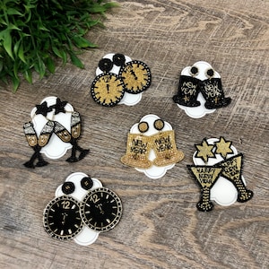 May include: Assortment of New Year's Eve themed beaded earrings.  The earrings feature a variety of designs including champagne flutes, clocks, and bells.  The earrings are all black and gold.