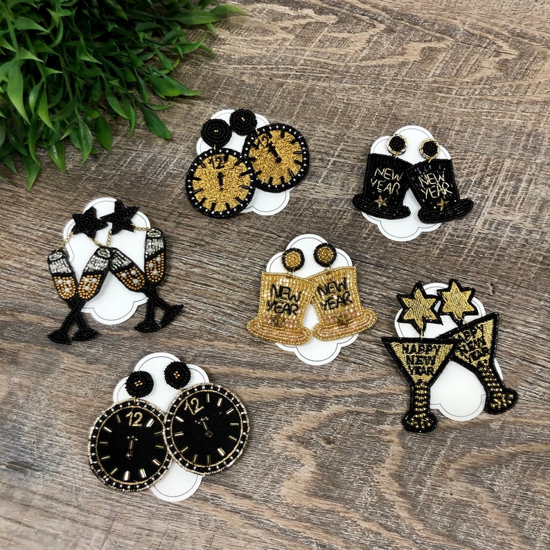 May include: Assortment of New Year's Eve themed beaded earrings.  The earrings feature a variety of designs including champagne flutes, clocks, and bells.  The earrings are all black and gold.