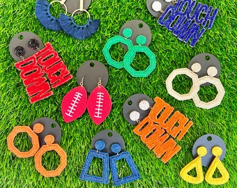 May include: Assortment of colorful beaded earrings with football-themed designs. The earrings feature various shapes, including footballs, stars, and geometric patterns. The earrings are made with colorful beads and have a playful and festive feel. Some of the earrings have the words "Touch Down" written on them.