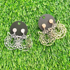 May include: Two pairs of earrings featuring a tiger face design. One pair is silver and the other is gold.