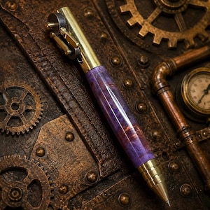 May include: A mechanical pen featuring a polished brass top and tip, with a central barrel made of marbled purple and brown resin. The top mechanism includes a small gear-like wheel and metal lever components, showcasing a metallic construction.