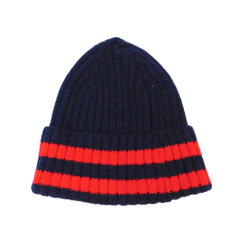 Puede incluir: Un gorro de punto azul marino con dos rayas rojas brillantes cerca del borde. El gorro es acanalado y tiene un dobladillo. Un gorro de invierno cl&aacute;sico.