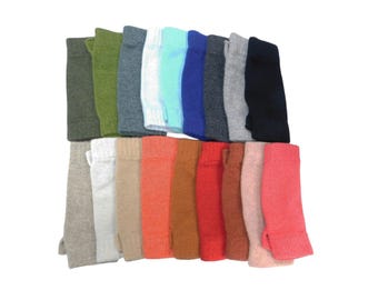 May include: A collection of fingerless gloves arranged in two rows, featuring a variety of solid colours including olive green, charcoal grey, white, light blue, royal blue, black, beige, orange, brown, red, terracotta, and bright pink.
