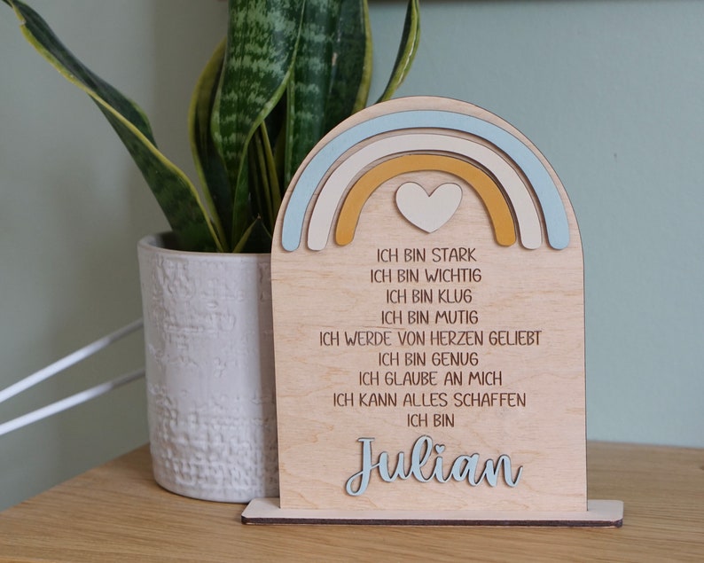 May include: Wooden rainbow-shaped sign with a heart in the center and the text "ICH BIN STARK, ICH BIN WICHTIG, ICH BIN KLUG, ICH BIN MUTIG, ICH WERDE VON HERZEN GELIEBT, ICH BIN GENUG, ICH GLAUBE AN MICH, ICH KANN ALLES SCHAFFEN, ICH BIN Julian"