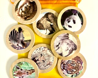 May include: A set of eight wooden animal tokens in a yellow drawstring bag. The tokens feature images of a lion, elephant, panda, zebra, rhinoceros, leopard, giraffe, and tiger.