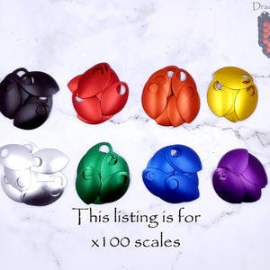 May include: A set of 100 metal scales in various colors, including black, red, silver, green, blue, and purple. The scales are arranged in groups of six, with each group showing a different color. The text "This listing is for x100 scales" is written below the scales.