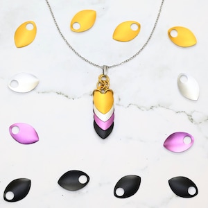 May include: A pendant necklace with a layered heart design in black, white, pink, and yellow. The pendant is surrounded by a variety of loose scales in black, white, pink, and yellow.