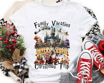 May include: White t-shirt with a graphic of a family vacation to Universal Studios during Christmas. The graphic features a castle, dinosaurs, and Santa Claus. The text "Family Vacation Universal Studios Christmas Trip" is printed on the shirt.