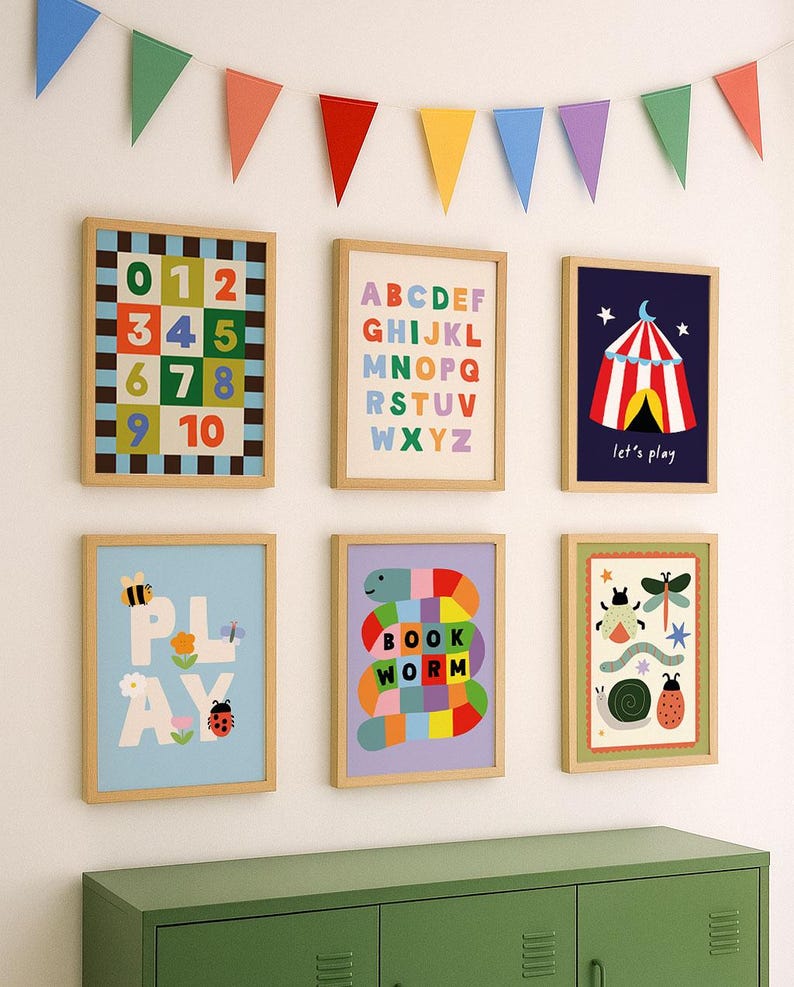 May include: A collection of six framed children's art prints with a wooden frame. The prints feature colorful illustrations of numbers, the alphabet, a circus tent, the word "PLAY", a bookworm, and other playful designs. A colorful banner hangs above.
