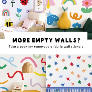 May include: Colorful wall stickers featuring various designs, including flowers, rainbows, butterflies, and stars. The image also shows a framed dog illustration, a yellow pear-shaped pillow, and the text "MORE EMPTY WALLS?" and "Kelsey Layne".