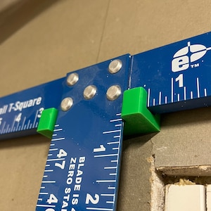 May include: A blue drywall T-square with green plastic end caps. The T-square has a ruler on both sides. The ruler on the right side reads "Blade is 47-7/8", "Zero starts at" and has markings for 1, 2, 3, and 4 inches.