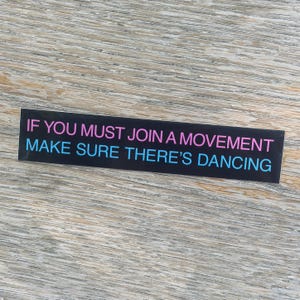 May include: A rectangular black sticker featuring the text IF YOU MUST JOIN A MOVEMENT in pink letters on the top line and MAKE SURE THERE'S DANCING in light blue letters on the bottom line. The sticker has a smooth finish and clean edges.