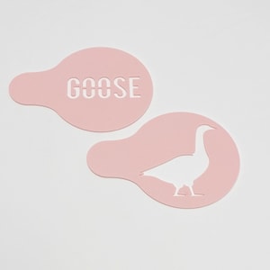 May include: Two pink plastic stencils, one with the word "GOOSE" cut out and the other with a goose silhouette cut out.