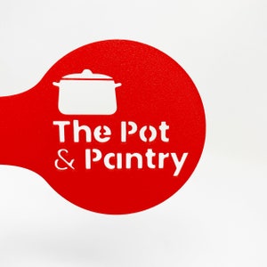May include: Red and white stencil with the text "The Pot & Pantry" and a silhouette of a pot with a lid.