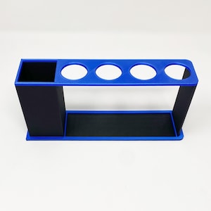 May include: A blue and black plastic organizer with four round slots and a rectangular compartment. The organizer is designed to hold items like pens, pencils, or paintbrushes.