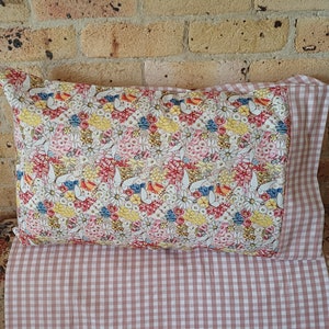 May include: A floral patterned pillow with a pink and white gingham pillowcase. The pillowcase has a white background with pink stripes.