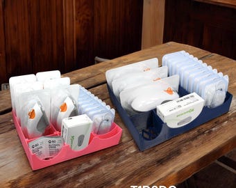 May include: Two pink and blue plastic organizers with compartments for storing medical supplies. The organizers are filled with clear plastic pouches and small white items. The text "T1D3DGEAR.com" and "Medical supplies NOT included" is visible at the bottom of the image.