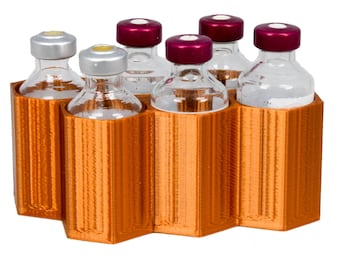 Könnte beinhalten: Orangener Plastik-Fläschchenhalter mit sechs klaren Glasfläschchen mit roten und silbernen Kappen.