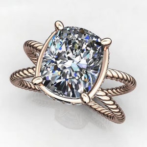 May include: A rose gold engagement ring with a large, cushion-cut diamond set in a twisted rope band.