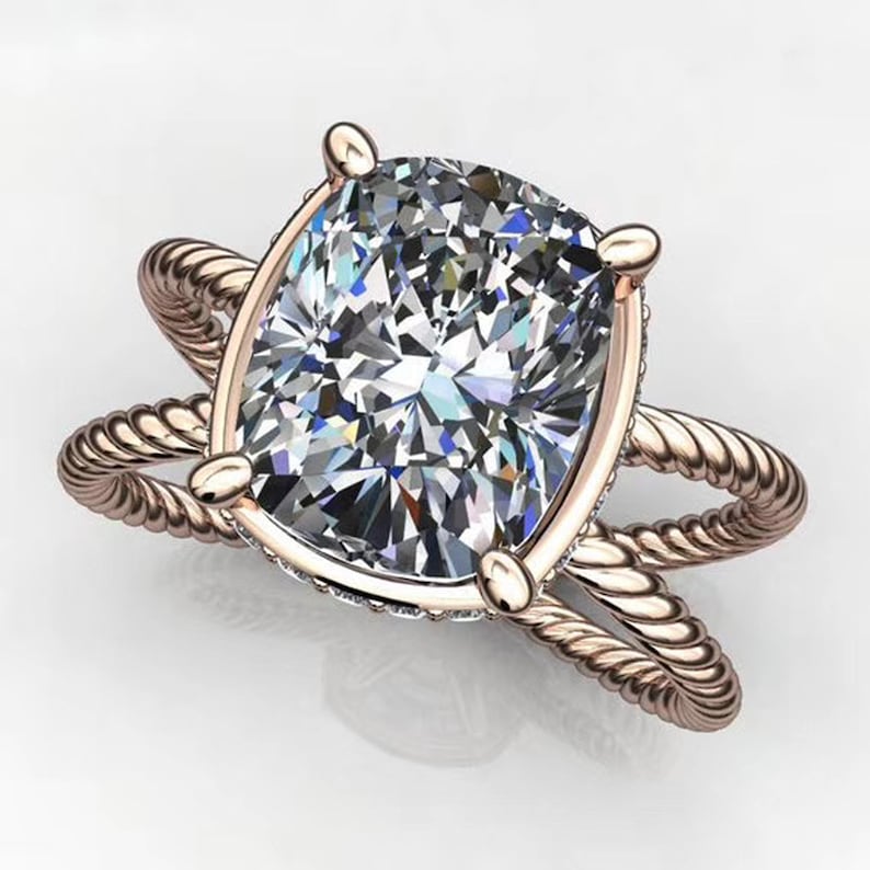 May include: A rose gold engagement ring with a large, cushion-cut diamond set in a twisted rope band.