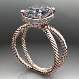 May include: A rose gold engagement ring with a large, clear, cushion-cut center stone surrounded by a halo of smaller diamonds. The band is a double-rope design.