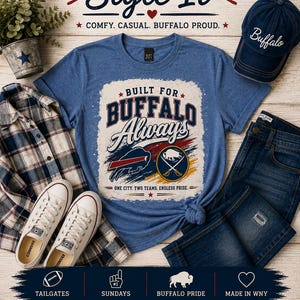 May include: A blue heathered t-shirt featuring the text BUILT FOR BUFFALO Always and logos of two sports teams. The shirt is displayed with a navy blue baseball cap with the word Buffalo, a plaid button-down shirt, white sneakers, and blue jeans.