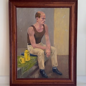 May include: Oil painting in a dark wood frame. The artwork depicts a person in a brown tank top and tan pants, seated with a yellow teapot and mug. The background is a muted palette of gray and yellow, with a green surface.