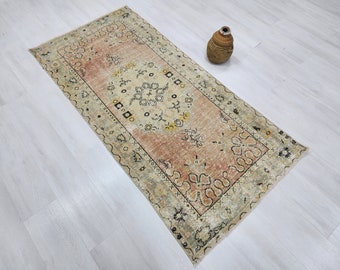 Puede incluir: Una alfombra vintage con fondo beige y centro color melocotón. La alfombra tiene un patrón floral con acentos negros y amarillos. La alfombra mide aproximadamente 60 cm por 90 cm.