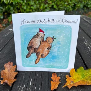 Carte de Noël loutre, loutres se tenant la main, jolie carte loutre, jolie carte de Noël.