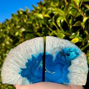 Peut inclure: Une paire de serre-livres en agate bleue avec des motifs blancs et bleus. Les serre-livres sont faits d'agate naturelle et ont une forme unique et organique.