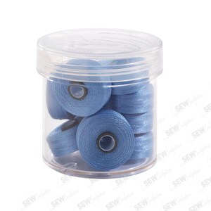 May include: A clear plastic container filled with several spools of light blue thread. The thread spools are neatly stacked inside the container, which has a clear lid. The thread appears to be a solid color, and the container is set against a white background.