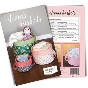 May include: A sewing pattern titled Olivia's Baskets featuring three round fabric baskets in green floral, pink floral, and grey floral prints. The pattern includes yardage requirements, a doll, and books inside the baskets, with a barcode.