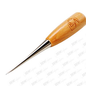 May include: A sewing awl with a wooden handle and a silver-colored metal tip. The handle is light brown and has the engraved text "ByA". The awl is designed for piercing fabric and leather.