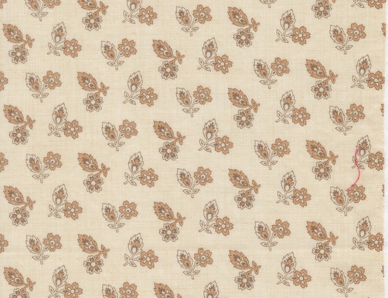 Może przedstawiać: Kremowa tkanina z powtarzającym się wzorem brązowych i beżowych motyw&oacute;w kwiatowych i liści. Wz&oacute;r przedstawia stylizowane kwiaty i liście ułożone w małe grupy na powierzchni. Tkanina ma subtelny, teksturowany wygląd.